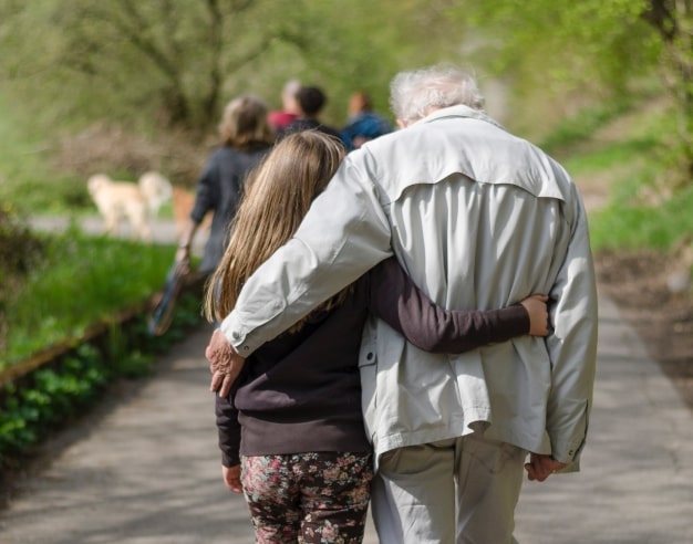 grandfather and daughter walk half-embraced